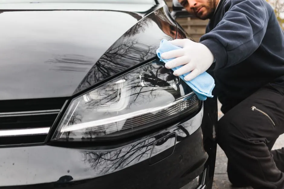 detailer gently lifting a bird dropping off car paint with a microfibre cloth and quick detailer