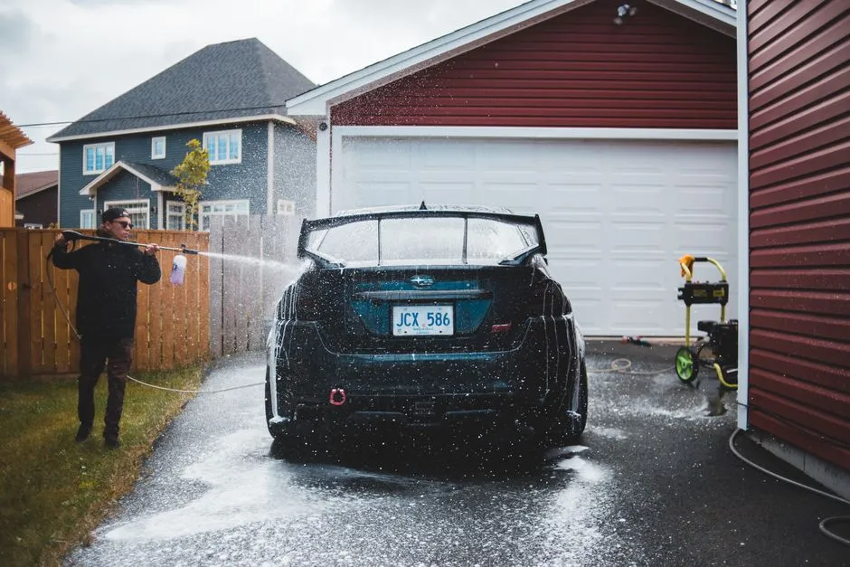 hand washing a car with fresh water to rinse salt off the paint